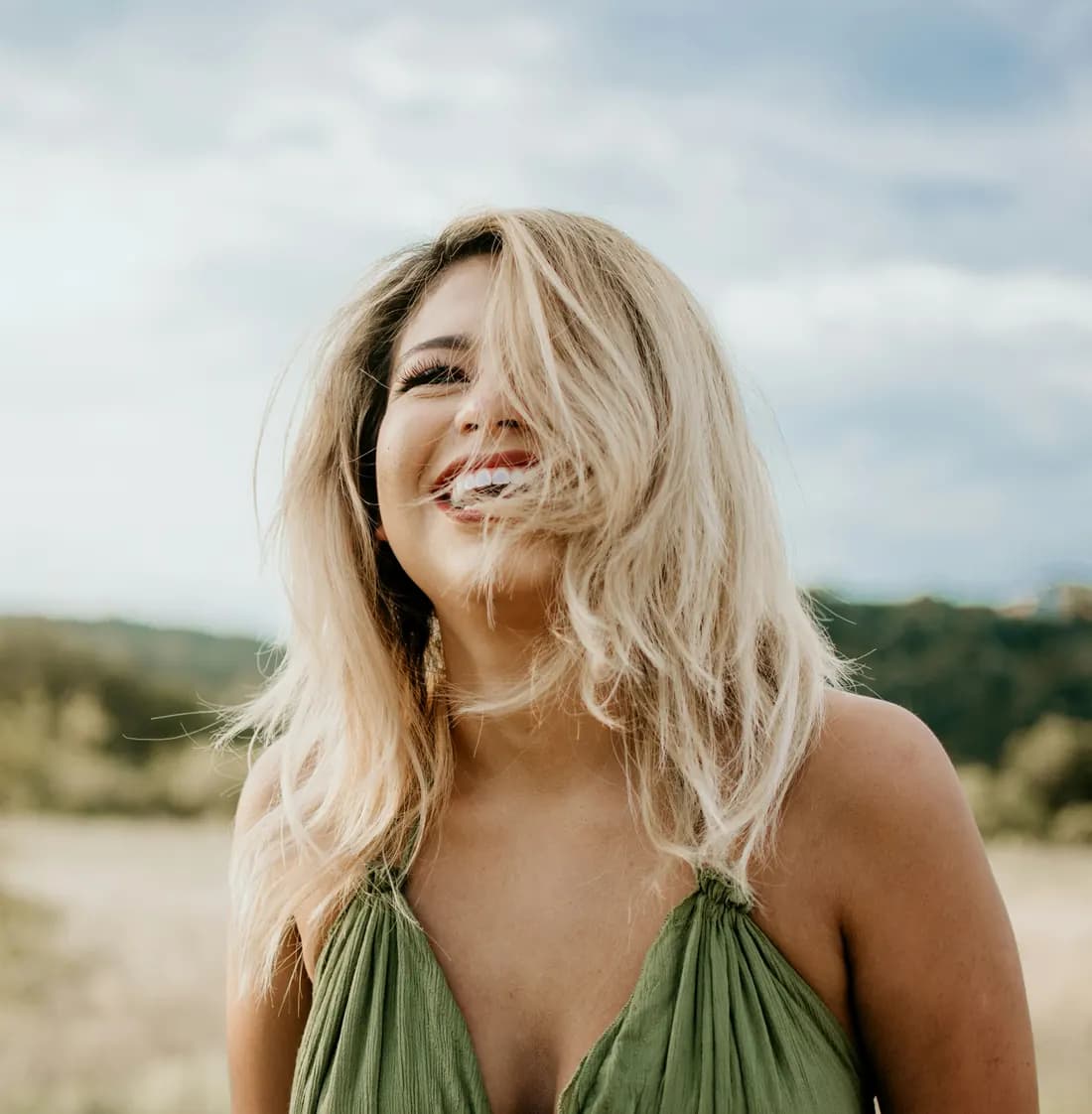 Mujer sonriendo al aire libre, con el pelo al viento
